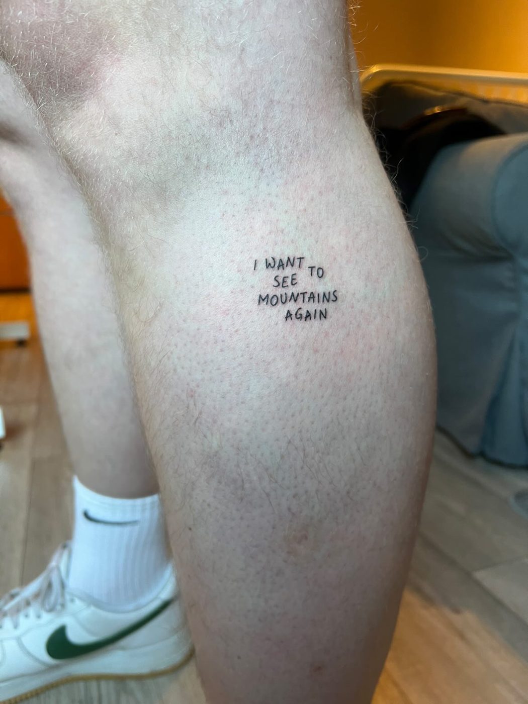 Fine-line lettering tattoo 'I want to see mountains again' by Linéa D'amore